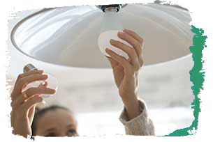 Woman replacing incandescent bulb for an energy saving bulb
