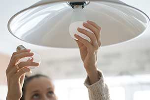 Woman replacing incandescent bulb for an energy saving bulb